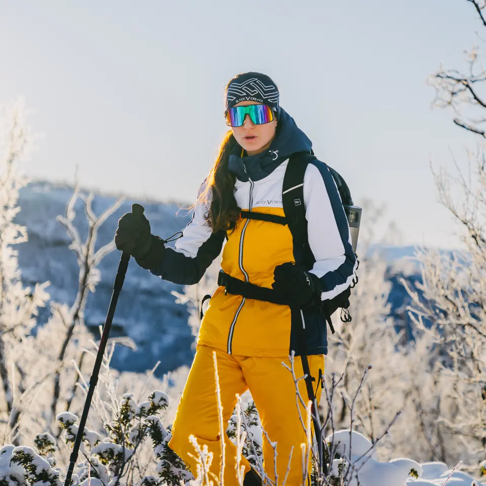 Kvinne vandrer i et snødekt landskap